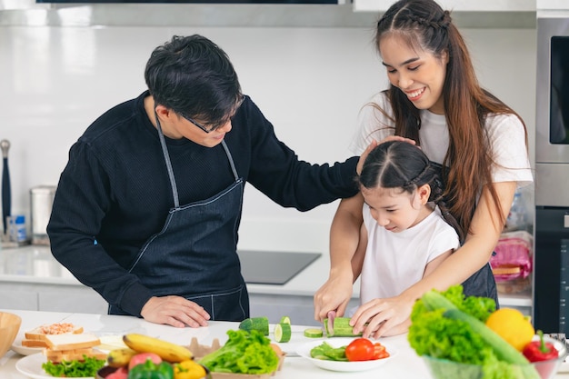 Asiatische Familienmenschen genießen es, Kindern beizubringen, zu Hause gesundes Essen mit einem Messer zu kochen