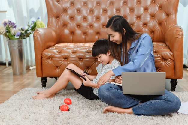 Asiatische Familienzusammengehörigkeit zu Hause. Mutter unterrichtet Kind für Online-Lernausbildung. Neuer normaler Lebensstil.