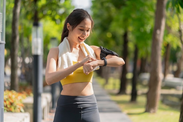 Asiatische fitness-frau, die vor dem lauftraining während des morgendlichen trainings eine smartwatch einrichtet