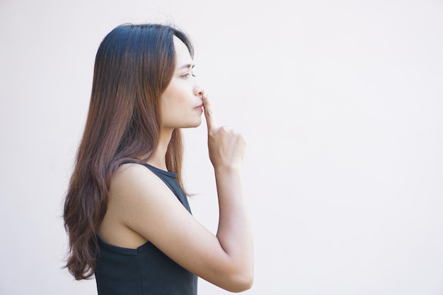 Asiatische Frau bedeckt ihren Mund mit ihrem Finger