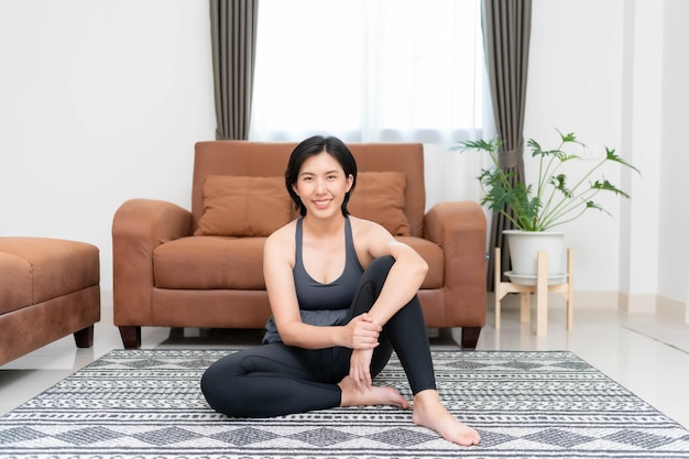 Asiatische Frau beim Yoga und Stretching im Wohnzimmer zu Hause Das Konzept der Übung, um einen gesunden Körper für sich selbst zu schaffen