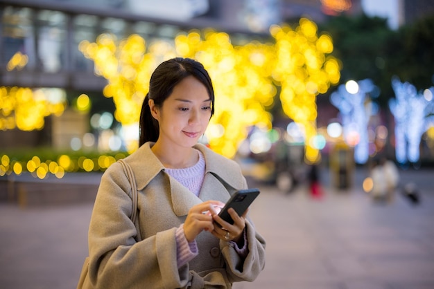 Asiatische Frau benutzt nachts in der Stadt ein Handy