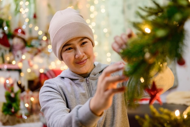 Asiatische Frau dekorieren für Weihnachten allein zu Hause. Familie feiern und ein frohes neues Jahr zu Hause.