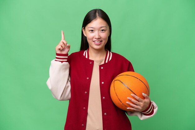 Asiatische Frau des jungen Basketballspielers über lokalisiertem Hintergrund, der eine großartige Idee zeigt