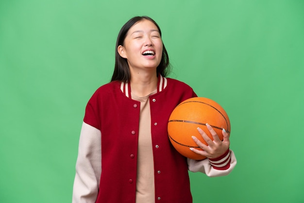 Asiatische Frau des jungen Basketballspielers über lokalisiertem Hintergrundlachen