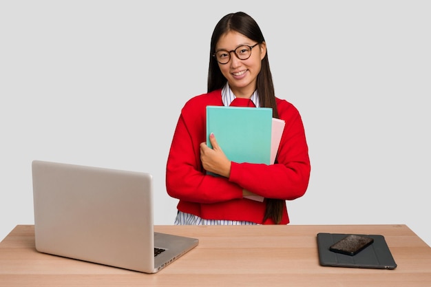 Asiatische frau des jungen studenten an einem arbeitsplatz mit einem laptop lokalisiert