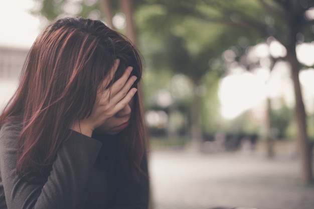 Asiatische Frau, die alleine und deprimiert sitzt, Porträt der müden jungen Frau. Depression