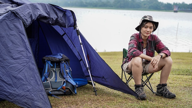 Asiatische Frau, die am Reservoir kampiert und sich in Stuhl setzt