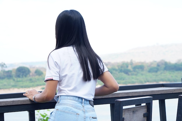 Asiatische Frau, die auf dem Balkon sitzt und die Landschaft betrachtet