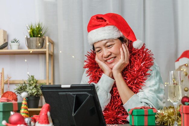 Asiatische Frau, die Champagner toastet, feiert Neujahr und Weihnachtsfeier-Videoanruf mit Freunden zu Hause