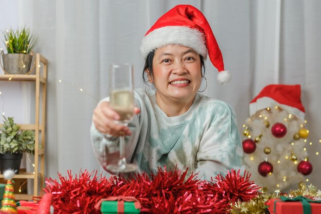 Asiatische Frau, die Champagner toastet, feiert Neujahr und Weihnachtsfeier-Videoanruf mit Freunden zu Hause