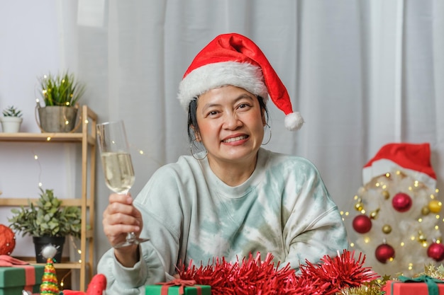 Asiatische Frau, die Champagner toastet, feiert Neujahr und Weihnachtsfeier-Videoanruf mit Freunden zu Hause