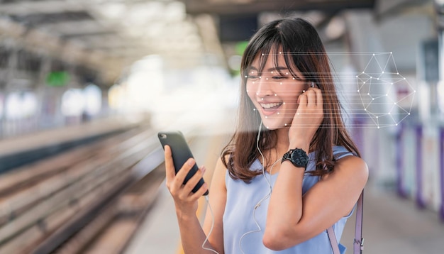 Asiatische Frau, die die Gesichtserkennung über ein Smartphone verwendet und die Musik bei Railroad hört