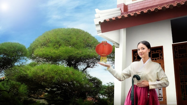 Asiatische Frau, die ein traditionelles koreanisches Nationalkostüm Hanbok trägt, das mit offenen Handflächen steht