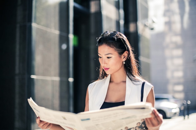 Asiatische Frau, die eine Zeitung liest