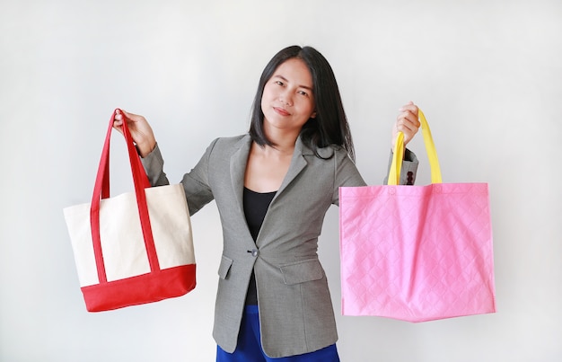 Asiatische Frau, die einen Baumwollstoffbeutel und einen rosa Recyclingbeutel hält