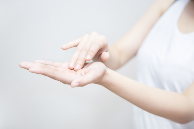 Asiatische frau, die feuchtigkeitscreme auf ihrer hand anwendet