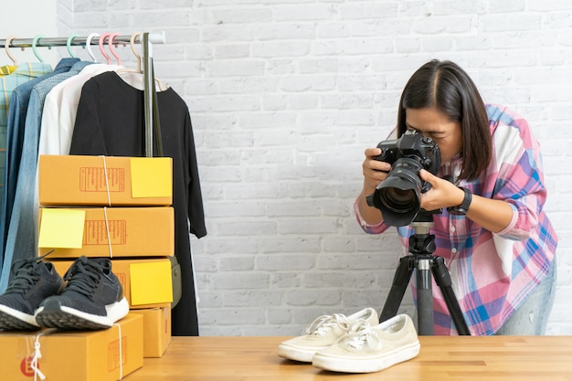 Asiatische Frau, die Foto zu Schuhen mit Digitalkamera für Post zum Online-Verkauf im Internet nimmt
