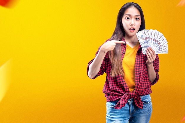 Asiatische Frau, die Geld mit farbigem Hintergrund hält