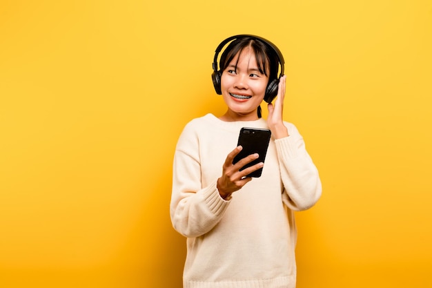 Asiatische Frau, die gerne telefoniert und Musik hört Entspannung mit Musik An einem angenehmen Tag Tanz- und Entspannungskonzept, das online Musik hört