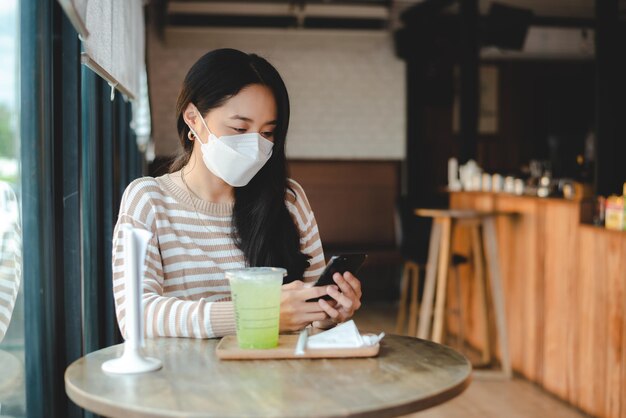 Asiatische frau, die getrennt im restaurant sitzt und isst, hält soziale distanz, um covid19 zu verhindern