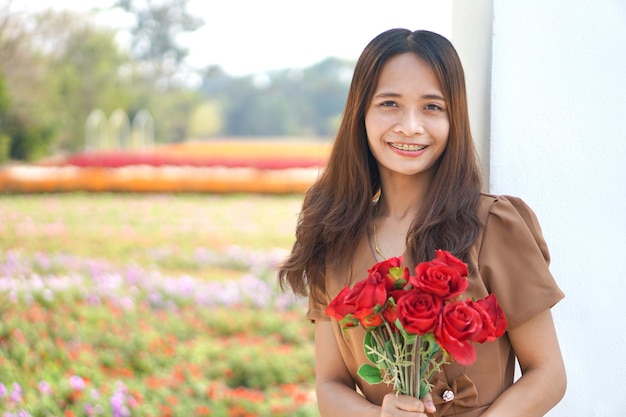Asiatische Frau, die glücklich unter schönen Blumen lächelt