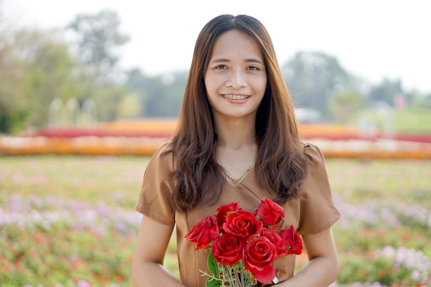 Asiatische Frau, die glücklich unter schönen Blumen lächelt