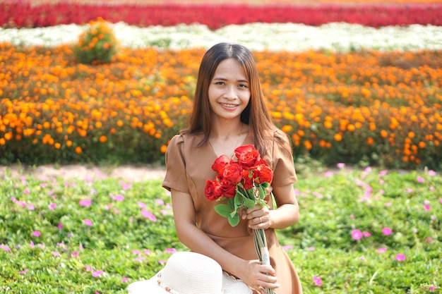 Asiatische Frau, die glücklich unter schönen Blumen lächelt