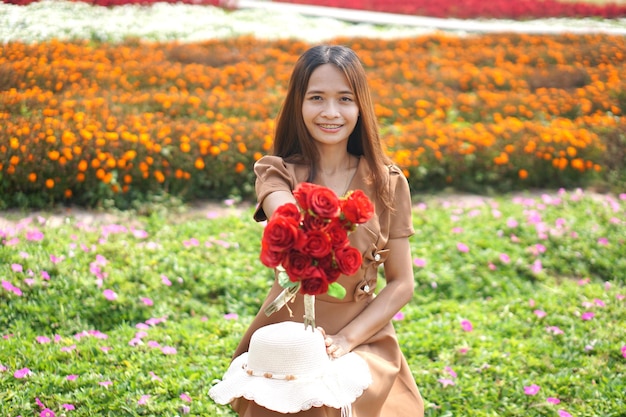 Asiatische Frau, die glücklich unter schönen Blumen lächelt