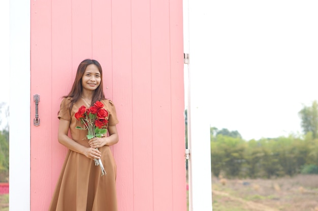 Asiatische Frau, die glücklich unter schönen Blumen lächelt