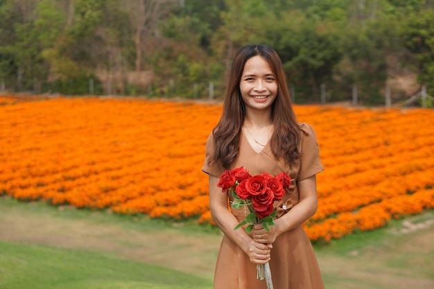 Asiatische Frau, die glücklich unter schönen Blumen lächelt
