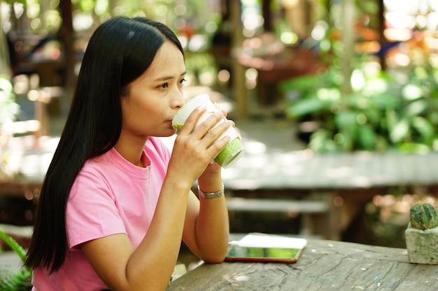 Asiatische Frau, die grünen Tee in einem Café trinkt