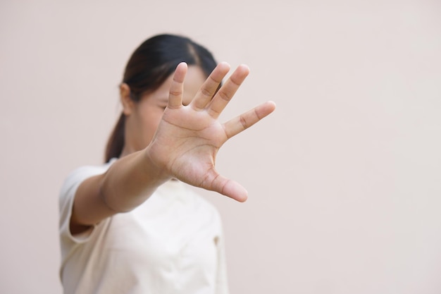 Asiatische Frau, die ihre Hände benutzt, um sich vor ankommenden Gefahren zu schützen