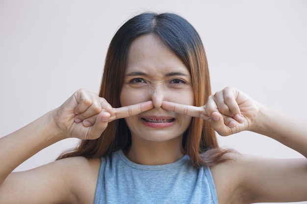 Asiatische Frau, die ihre Nase wegen eines schlechten Geruchs mit den Händen bedeckt