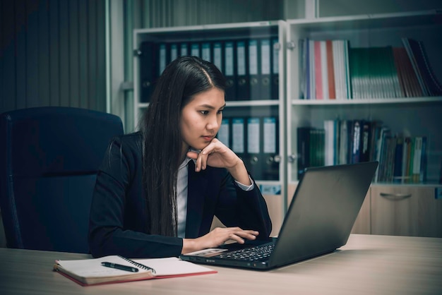 Asiatische Frau, die im Büro arbeitet, junge Geschäftsfrau, gestresst von Arbeitsüberlastung mit einer Menge Akte auf dem Schreibtisch. Thailand-Leute denken etwas