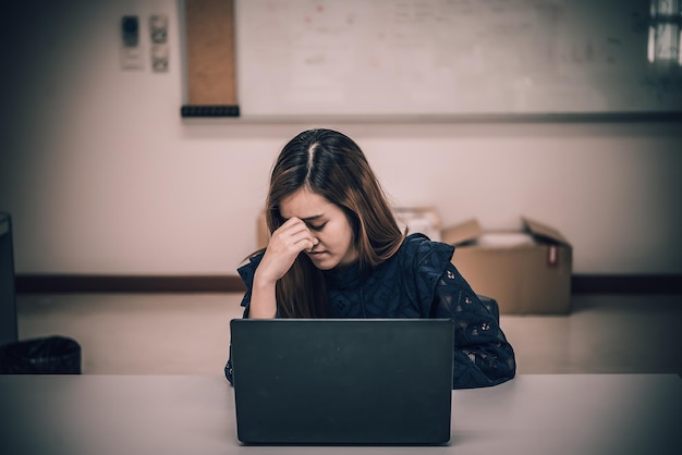 Asiatische Frau, die im Büro arbeitet, junge Geschäftsfrau, gestresst von Arbeitsüberlastung mit vielen Akten auf dem Schreibtisch