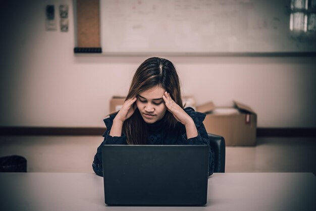Asiatische Frau, die im Büro arbeitet, junge Geschäftsfrau, gestresst von Arbeitsüberlastung mit vielen Akten auf dem Schreibtisch