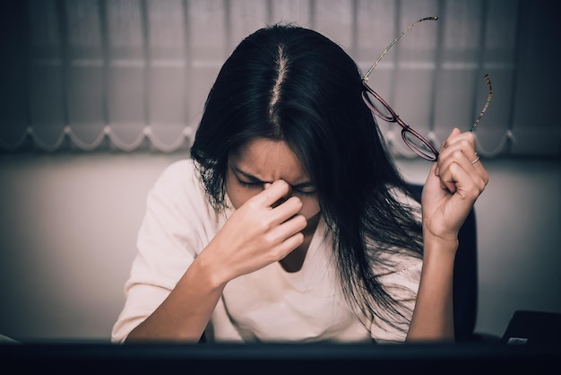 Asiatische Frau, die im Büro arbeitet, junge Geschäftsfrau, gestresst von Arbeitsüberlastung mit vielen Akten auf dem Schreibtisch