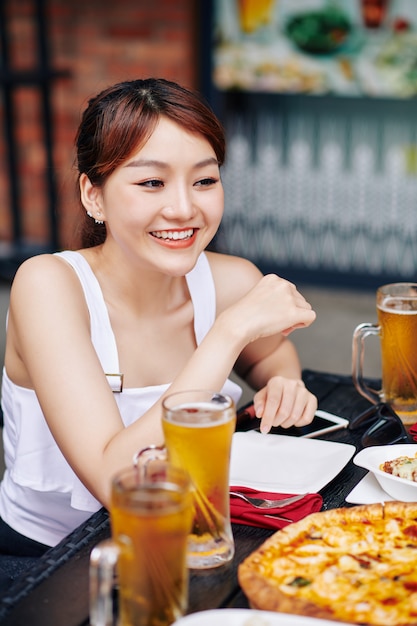 Asiatische Frau, die im Café sitzt