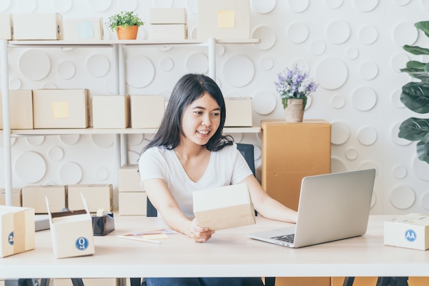 Asiatische Frau, die im Lieferservice mit Laptop arbeitet