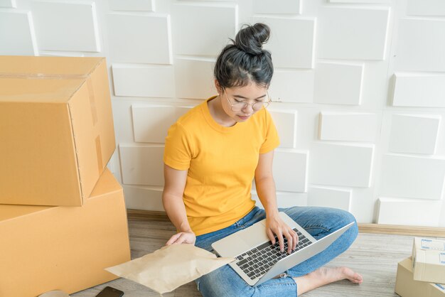 Asiatische Frau, die im Lieferservice mit Laptop arbeitet