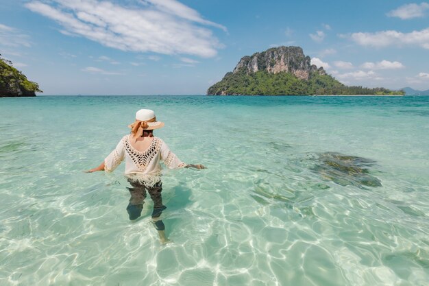 Asiatische frau, die im meer steht und spielt und mit schöner natur in ihrem urlaub genießt. sommerferienkonzept.