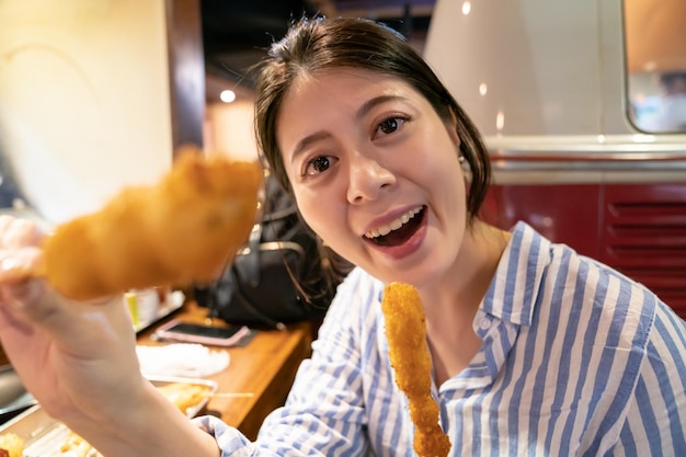 asiatische frau, die jemandem japanisches essen füttert. im Izakaya, Osaka.