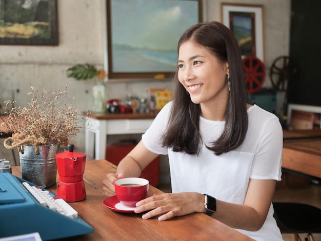 Asiatische Frau, die Kaffee im Kaffeecafé trinkt