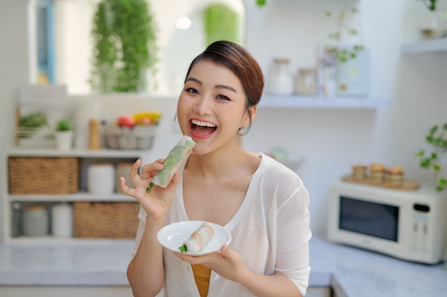 Asiatische Frau, die leckere traditionelle Frühlingsrollen isst
