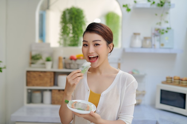 Asiatische Frau, die leckere traditionelle Frühlingsrollen isst