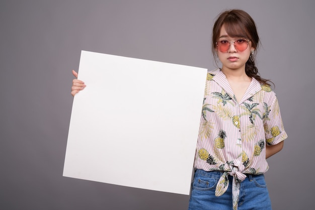 Asiatische Frau, die leere weiße Tafel mit Copyspace hält