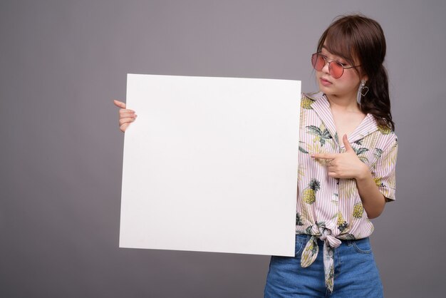 Asiatische Frau, die leere weiße Tafel mit Copyspace hält