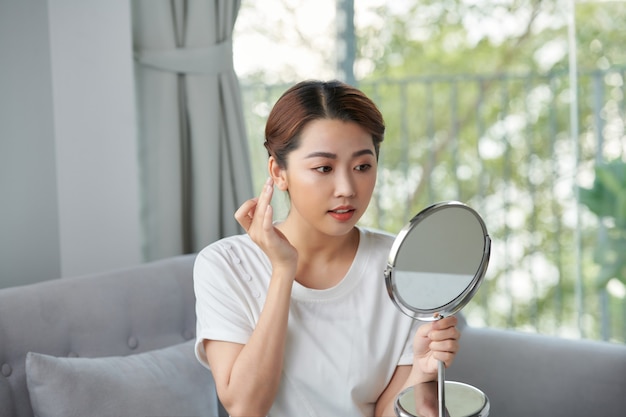 Asiatische Frau, die Make-up vor dem Spiegel sitzt