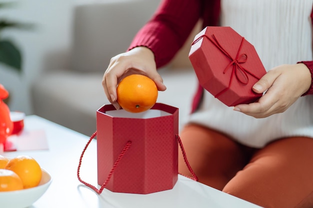 Asiatische Frau, die Mandarinen mit roter Geschenkbox hält, dankbares Geschenk Lunar New Year Chinese